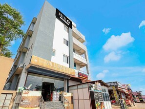 A multi-story building with a hotel named 'HOTEL SHIVALIKA' on the top floor, a 'HILL MART' grocery store on the ground floor, and a small kiosk with a sign that reads 'Catch.' - Deluxe Room Hotel Shivalika (Jaipur)