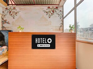 A hotel reception desk with a sign indicating it is OYO-Serviced. - Deluxe Room Hotel Shivalika (Jaipur)