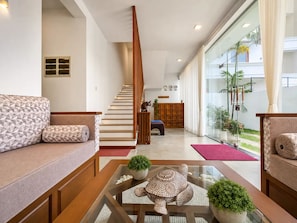 Un interior moderno con escalera, zona de estar y vistas amplias a través de grandes ventanales.