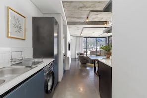 A modern kitchen with a dishwasher, a sink, and a large window offering a city view. - FortyOnL | Stunning City and Table Mountain Views (Cape Town)