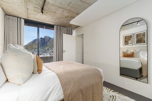 A bedroom with a large bed, a mirror, and a view of mountains. - FortyOnL | Stunning City and Table Mountain Views (Cape Town)