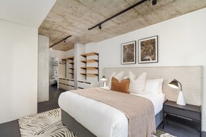 A modern bedroom with a large bed, bedside tables, a wardrobe, and a bathroom visible through an open door. - FortyOnL | Stunning City and Table Mountain Views (Cape Town)