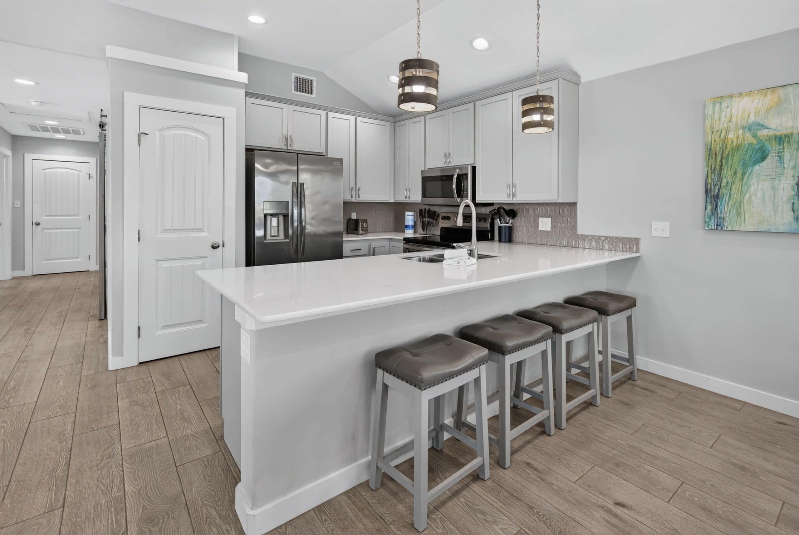 A modern kitchen with a central island, bar stools, and stainless steel appliances.