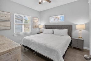 A bedroom with a large bed, two bedside tables, a dresser, and artwork on the walls. - Fluorescent Beauty 4BR Home (Port Aransas)