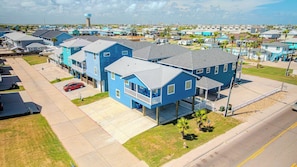 A residential area with multiple two-story houses, a parking lot, and a water tower in the background. - Fluorescent Beauty 4BR Home (Port Aransas)