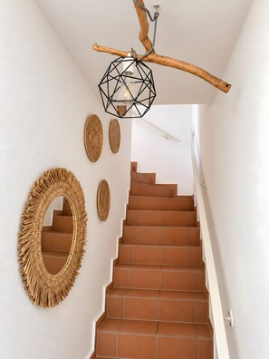 A staircase with brown tiles, a geometric pendant light, and woven wall decor. - Holiday Home 'Natürlich Am Bodden' with Lake View, Private Terrace and Wi-Fi (Fuhlendorf)