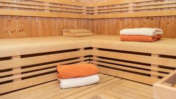 A sauna with wooden benches and benches, towels, and a bench with a towel on it.