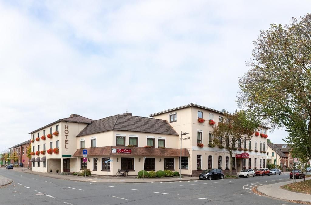 Un hôtel avec un restaurant au rez-de-chaussée, un vélo garé à l’extérieur et des voitures stationnées le long de la rue.