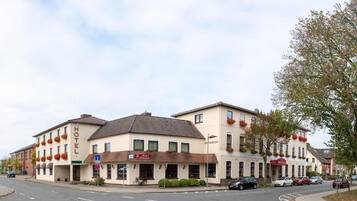 Un hôtel avec un restaurant au rez-de-chaussée, un vélo garé à l’extérieur et des voitures stationnées le long de la rue.