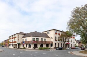 A hotel with a restaurant on the ground floor, a bike parked outside, and cars parked along the street. - Hotel Daub  (Bremervörde)