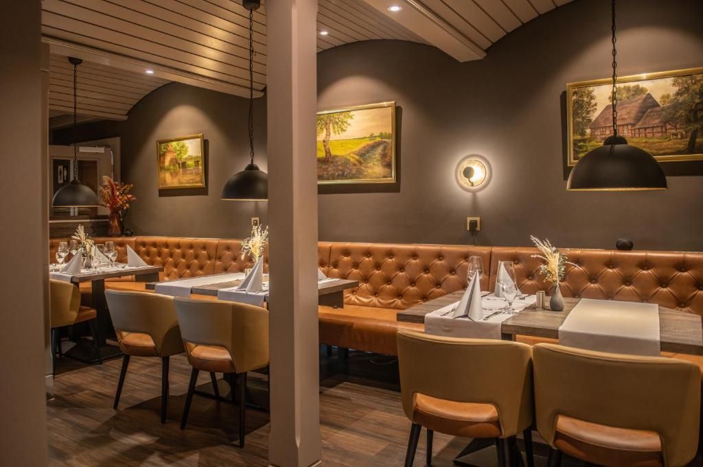 L’intérieur d’un restaurant présente un long banc en cuir marron, des tables rondes recouvertes de nappes blanches et un éclairage suspendu.