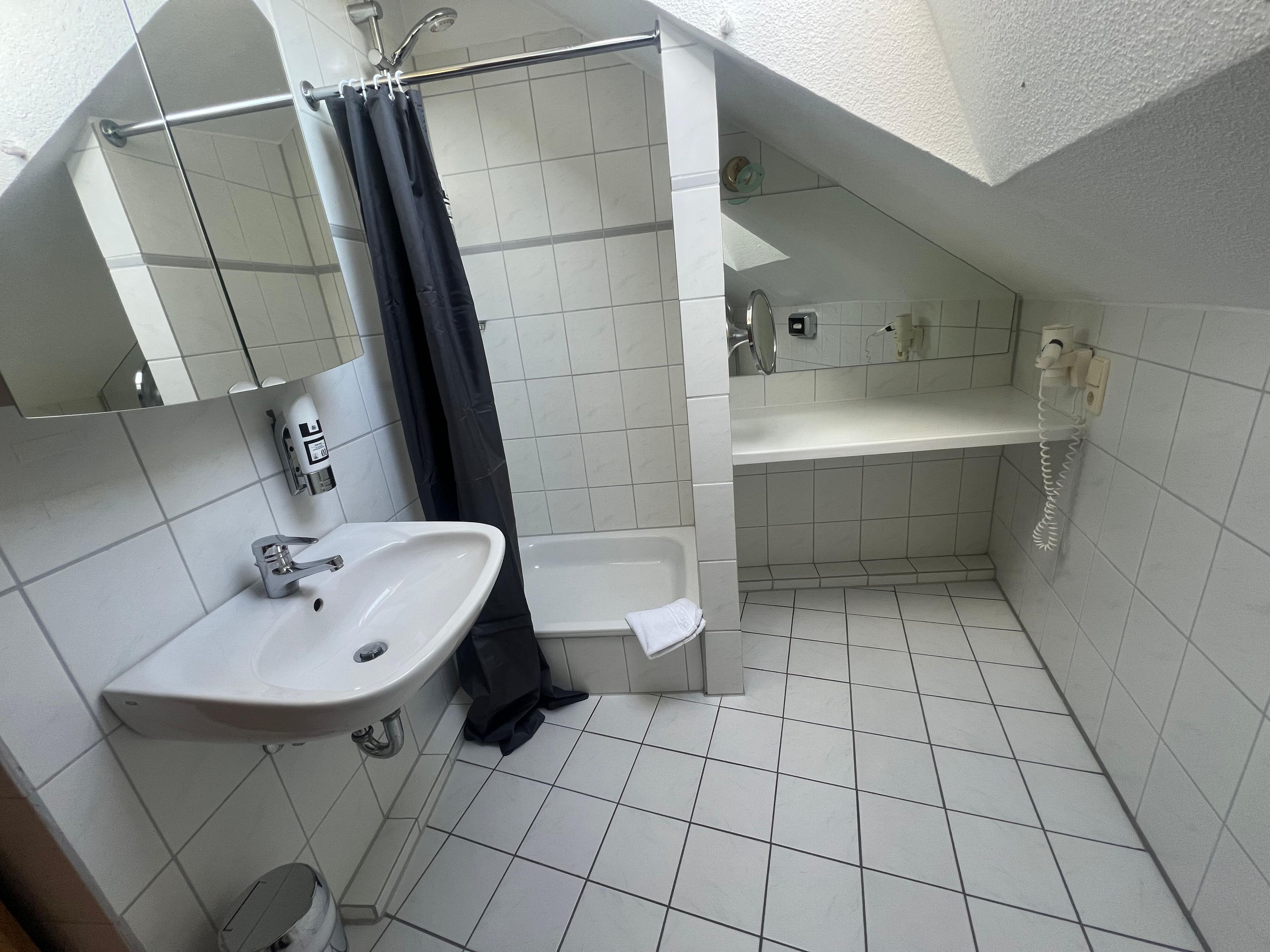 Een kleine badkamer met tegels, een wastafel, toilet en douche.