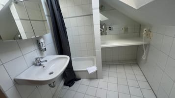 Een kleine badkamer met tegels, een wastafel, toilet en douche.