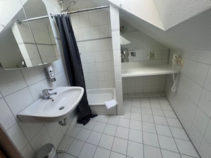 Casa de banho pequena com azulejos, incluindo lavatório, sanita e zona de duche.