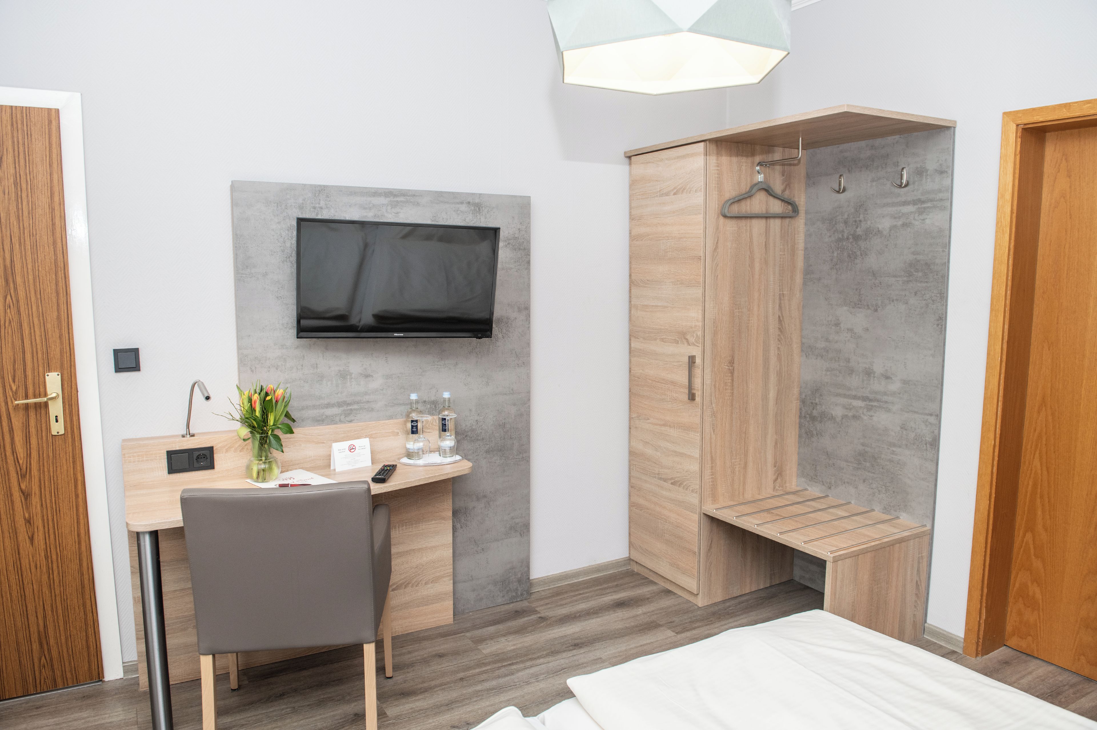 Habitació d'hotel moderna amb escriptori de fusta, televisió de pantalla plana, dutxa i llit.