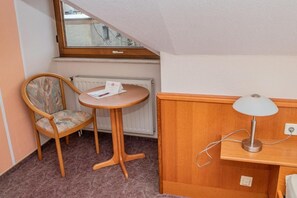 A small room with a wooden chair, a round table, a lamp, and a radiator. - Hotel Daub  (Bremervörde)
