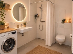 A modern bathroom with a washing machine, sink, shower, and toilet. - Modern worker's apartment with a balcony in Bestensee (Bestensee)