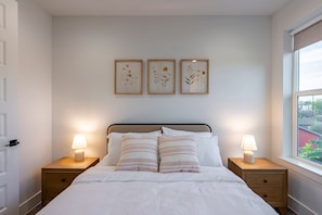 A bedroom with a bed, two bedside tables, and three framed botanical prints on the wall. - Family Retreat: Hot Tub, Game Loft, 3 Ensuites (Houston)
