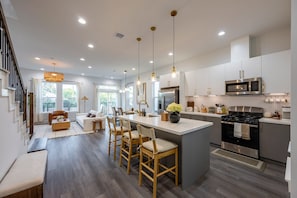 A modern kitchen with a central island, stainless steel appliances, and a dining area with a sofa and chairs. - Family Retreat: Hot Tub, Game Loft, 3 Ensuites (Houston)