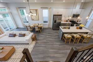 A modern kitchen with a built-in refrigerator, a dining area with a table and chairs, and a living room with a sofa and a coffee table. - Family Retreat: Hot Tub, Game Loft, 3 Ensuites (Houston)