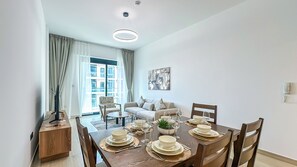 Een eetgedeelte met een houten tafel voor vier personen, een bank en een raam met gordijnen.