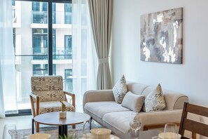 A modern living room with a sofa, armchairs, a coffee table, and a painting on the wall. - Modern 1BR apartment in Elysee 3 by Pantheon, Pool & Gym access (Dubai)