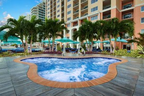Ein Hotelpool mit Whirlpool, Liegestühlen und Sonnenschirmen.