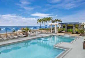 A pool area with lounge chairs and umbrellas, a clear sky, and a view of the ocean. - Marriott's BeachPlace Towers 1 Guest Room,1 King, Sofa Bed, Balcony-Beach Vacay (Fort Lauderdale)