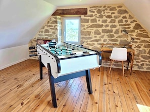 Una mesa de fútbol de mesa en una habitación con paredes de piedra y suelo de madera.