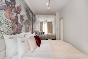 Un dormitorio moderno con una cama grande, un mural decorativo y vistas al cuarto contiguo.