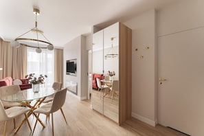 Un comedor moderno con mesa de vidrio, sillas blancas y suelo de madera.