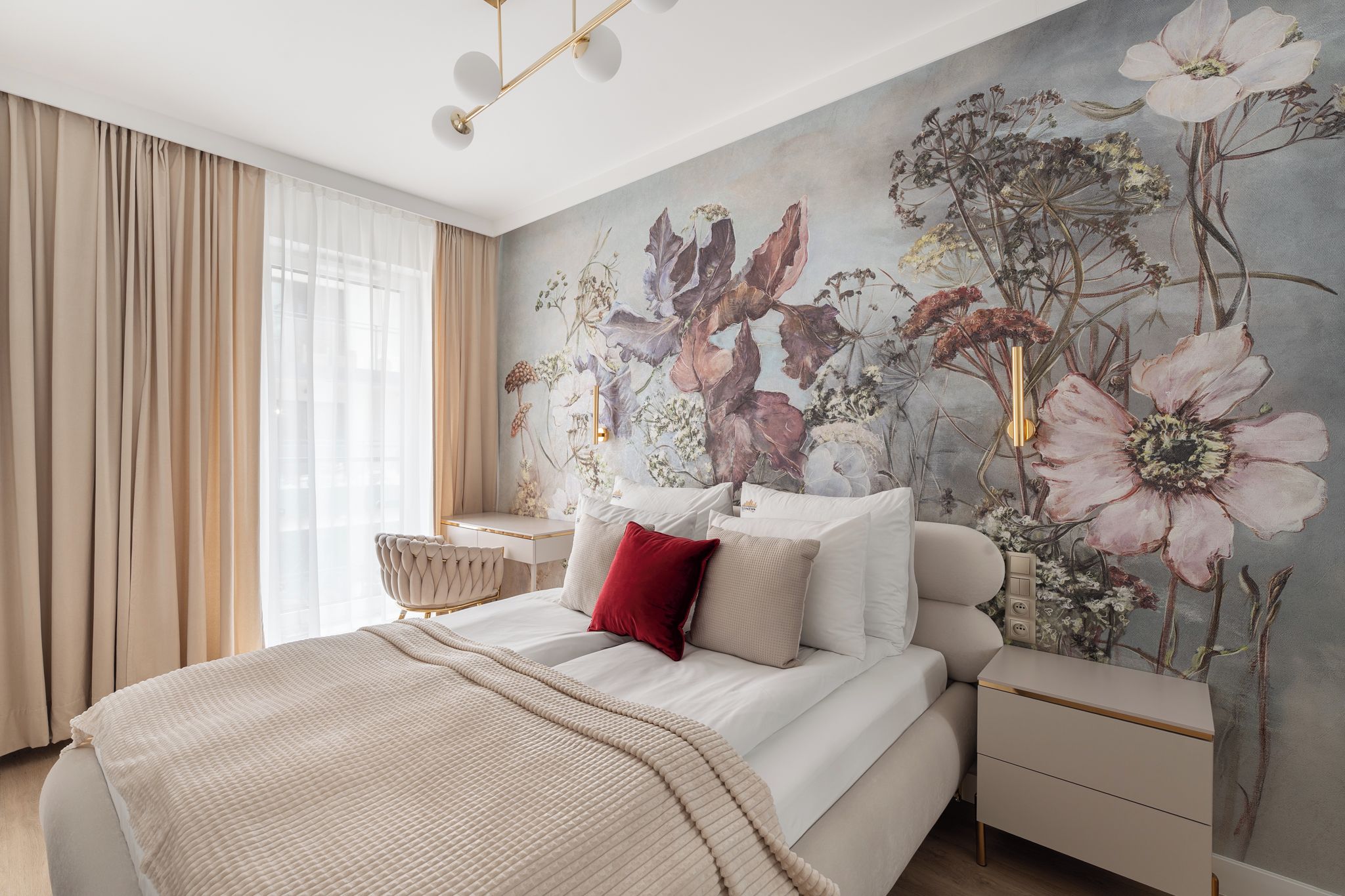 A bedroom with a large bed, a desk, and a wall mural.