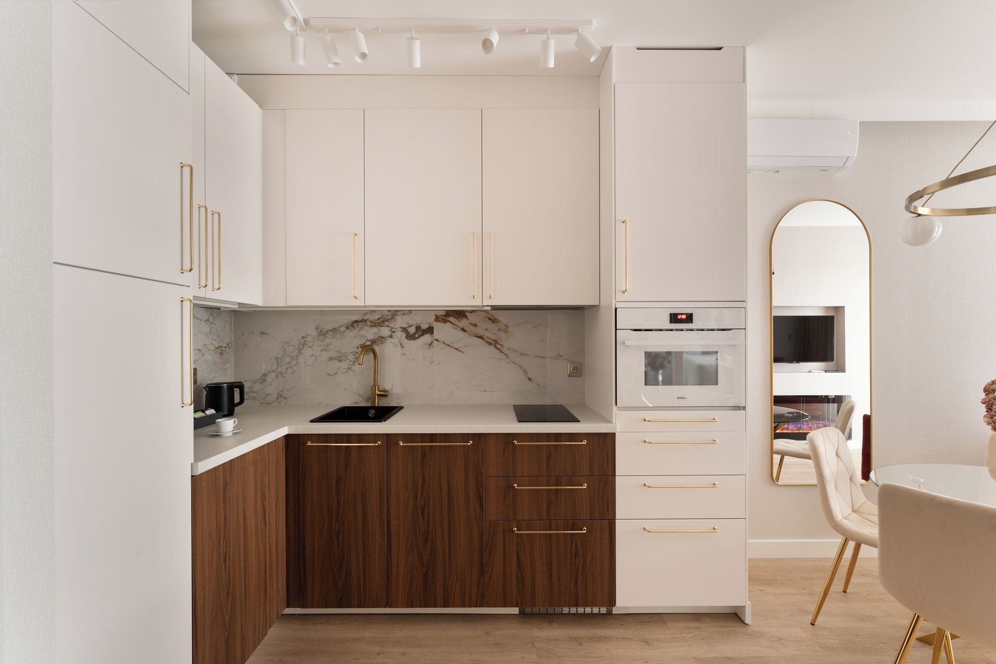 A modern kitchen with white cabinetry, a marble backsplash, and a built-in oven.