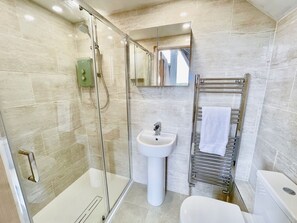 Een moderne badkamer met een douchecabine, een wastafel op voet en een handdoekhouder.