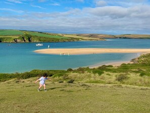 A coastal landscape with a sandy beach, grassy fields, and a body of water. - LUXURY LAKESIDE LODGE - Indoor POOL, own HOT TUB, PLAYROOM, on-site WATER SPORTS (St Columb Major)
