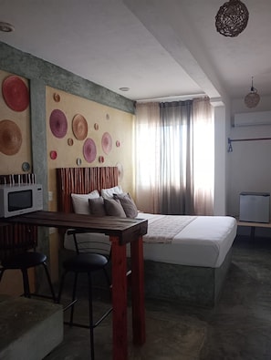 Un dormitorio con una cama, un escritorio con microondas y una silla.