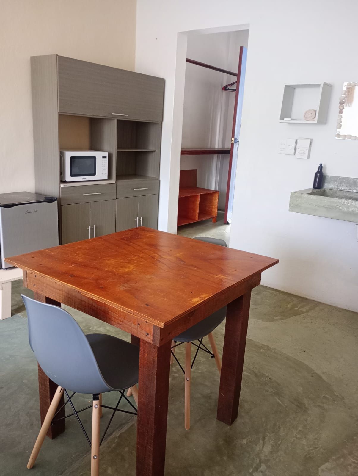 A compact kitchen with a microwave, cabinets, and a sink.