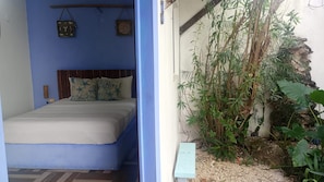 Una habitación con una cama, una pared azul y una pequeña zona de jardín con plantas.