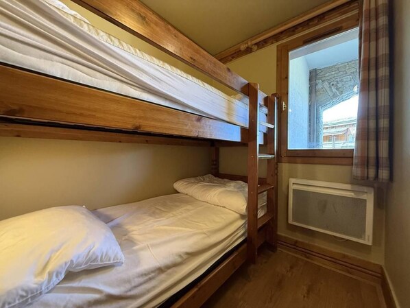 Ein Schlafzimmer mit Etagenbetten, einem Fenster und einer Heizung.