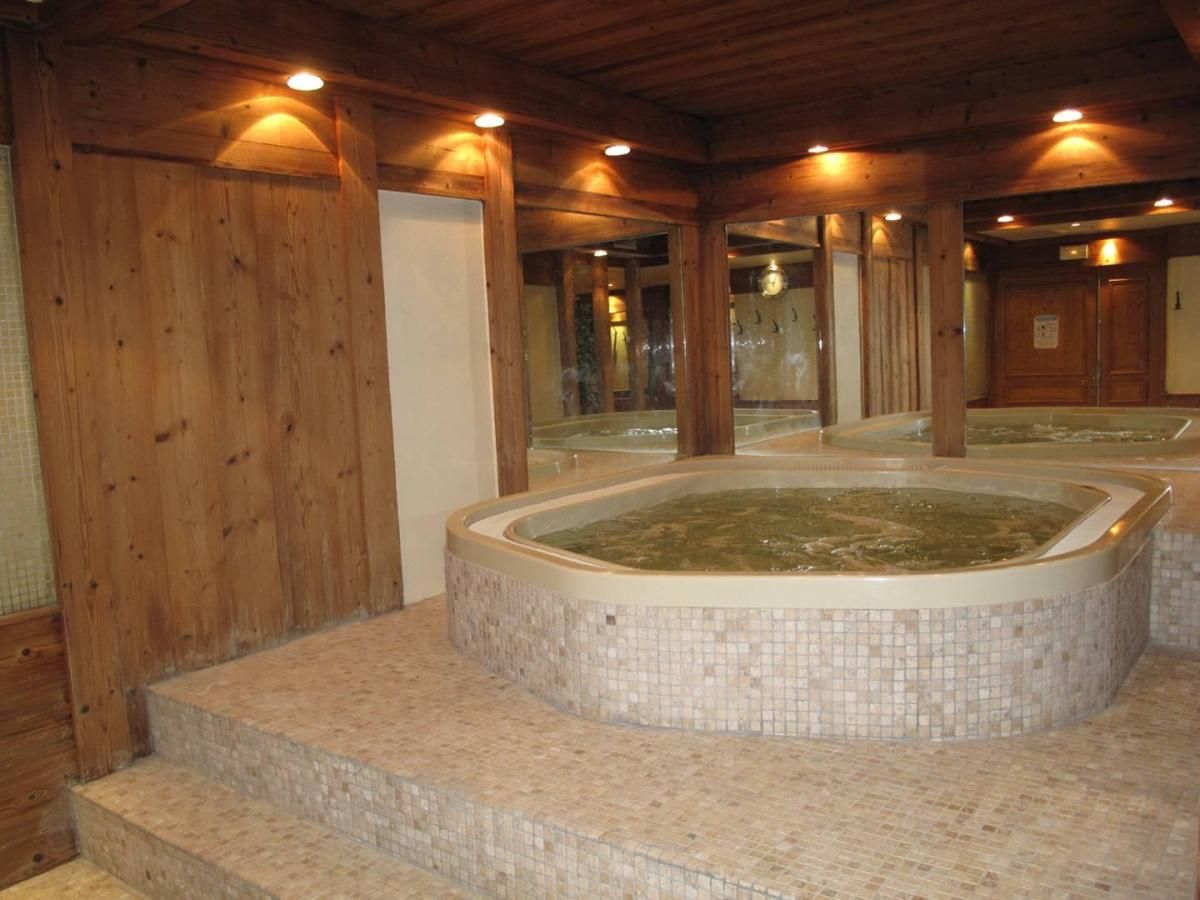 Un espace spa comprenant un jacuzzi, des murs en bois et un sol carrelé.