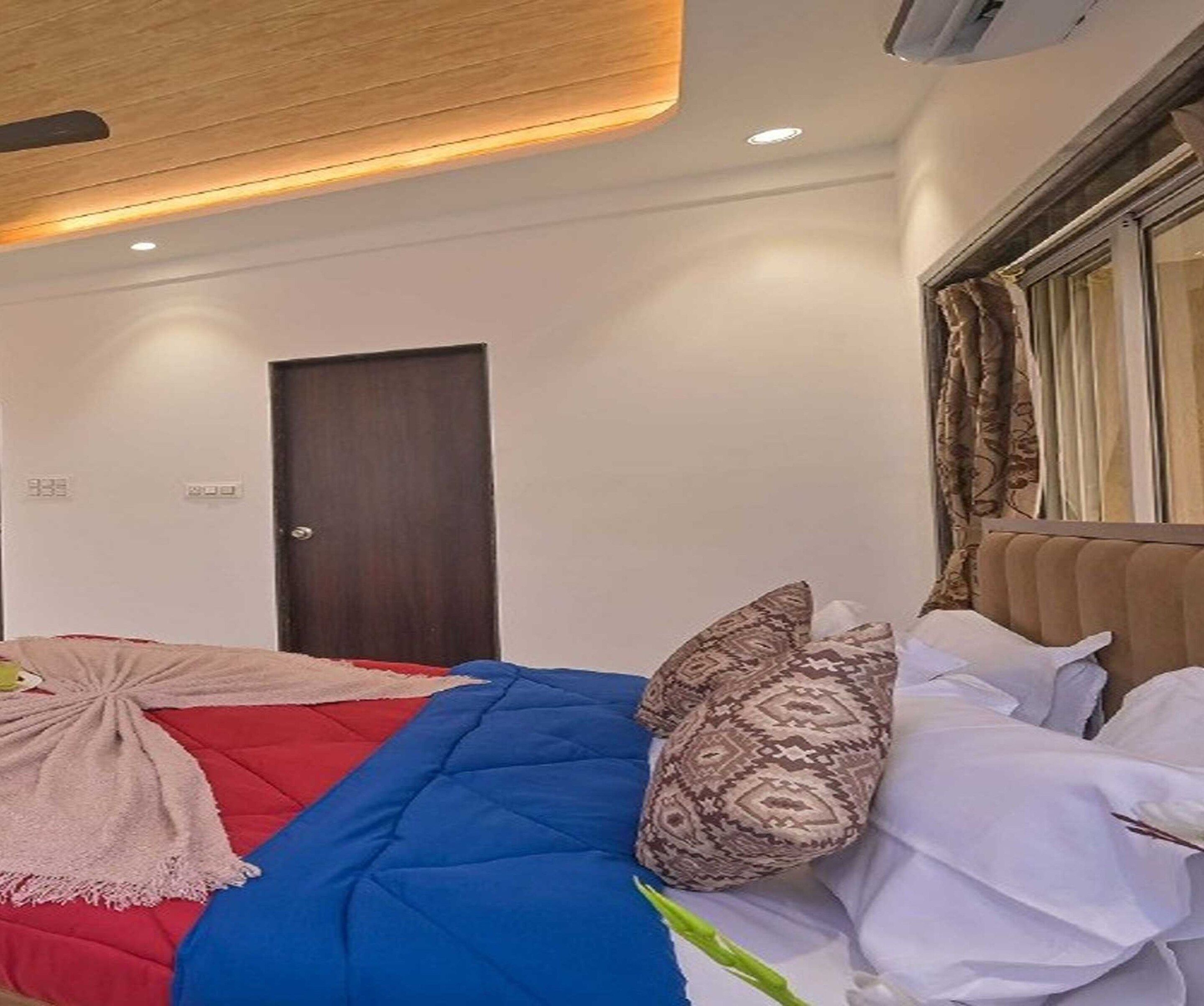 A hotel room with a bed, a door, and a window with curtains.