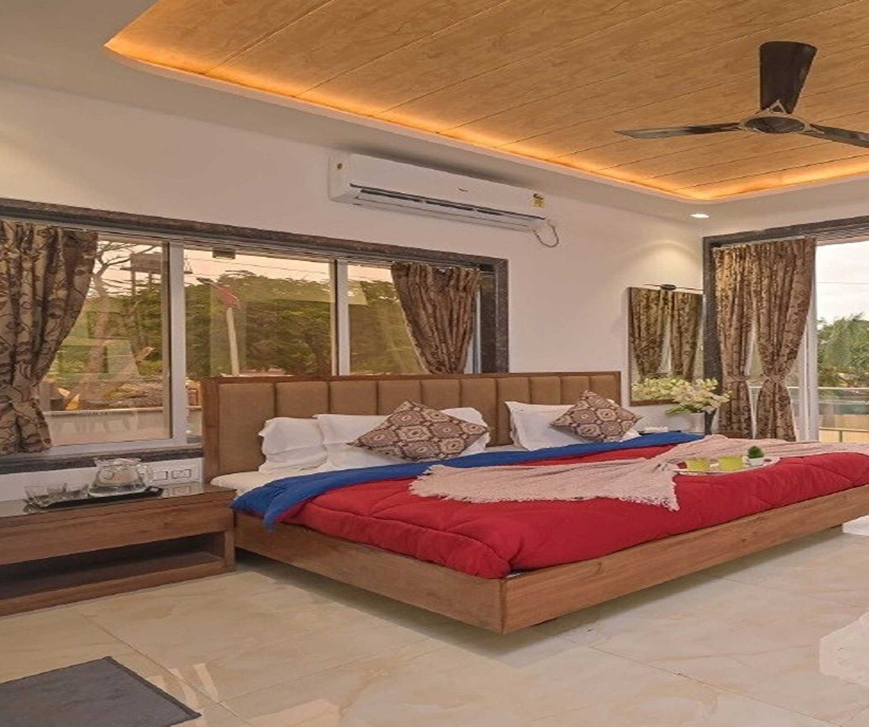 A bedroom with a large bed, a ceiling fan, and a window with curtains.