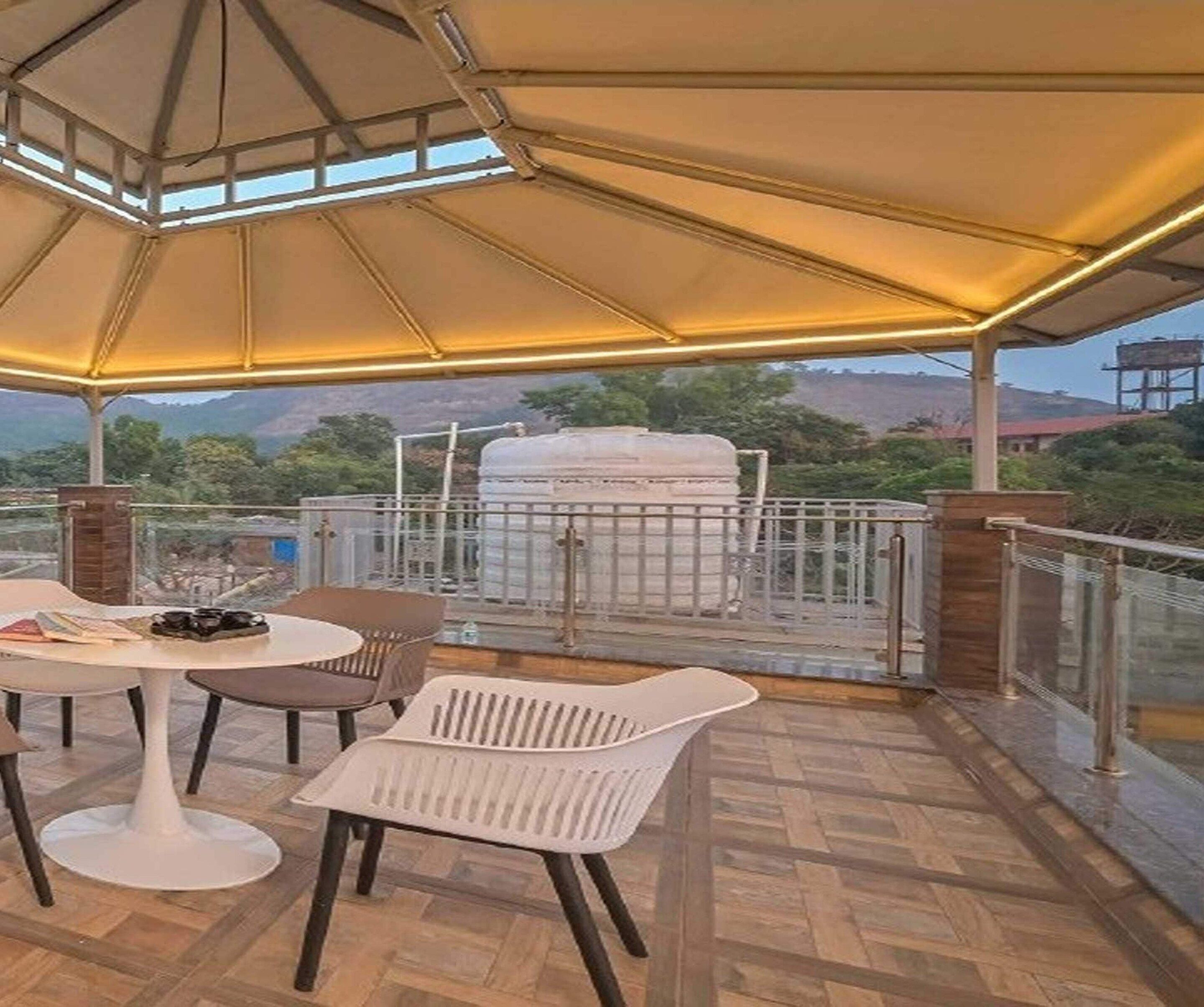An outdoor patio with a table and chairs, a barbecue grill, and a view of the surrounding landscape.