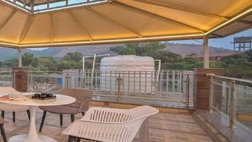 An outdoor patio with a table and chairs, a barbecue grill, and a view of the surrounding landscape.