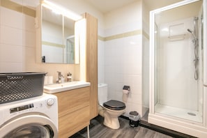 A modern bathroom with a washing machine, toilet, and shower. - Le Nid Grenoblois - Appart dans Grenoble pour 4 (Grenoble)