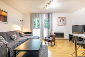 A modern living room with a sofa, a coffee table, a TV, and a fireplace. - Le Nid Grenoblois - Appart dans Grenoble pour 4 (Grenoble)