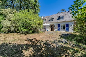 A two-story house with a stone facade, a front porch, and a small garden area. - Ty Arcouest - Proche de la plage (Ploubazlanec)