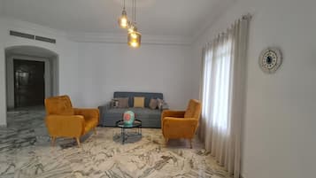 A living room with a sofa, two armchairs, a coffee table, and a decorative wall piece.