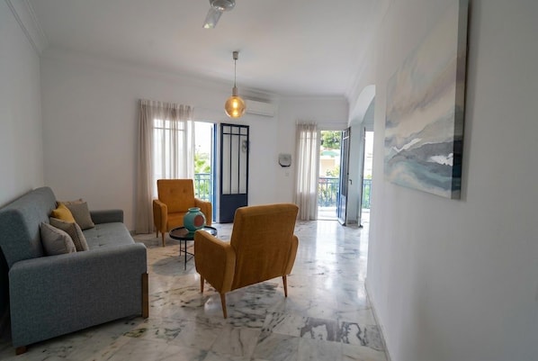 A modern living room with a sofa, armchairs, a coffee table, and a painting on the wall. - sandra 19 (Gammarth)
