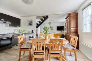 Cozinha moderna com área de jantar, cadeiras de madeira e escada para outro andar.